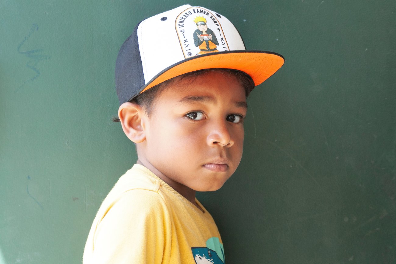 boy wearing hat standing in front of green background