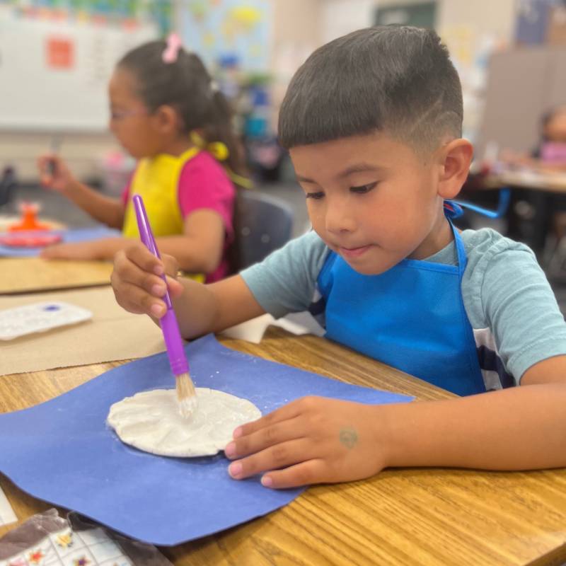 kid painting a hand clay shape